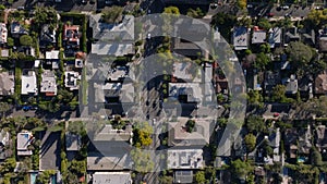 Top down panning shot of cars driving in streets of residential urban neighbourhood on sunny day. Los Angeles