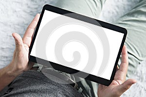 Top-down shot of digital tablet in young man's hands sititng comfortably on a sofa. Close up of man's hands holding tablet with