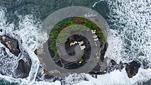 Top down Tanah Lot Temple on the rock in Sea. Ancient hinduism place of worship. Sunlight. Aerial view. Bali, Indonesia