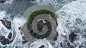 Top down Tanah Lot Temple on the rock in Sea. Ancient hinduism place of worship. Sunlight. Aerial view. Bali, Indonesia