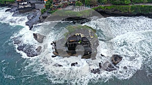 Top down Tanah Lot Temple on the rock in Sea. Ancient hinduism place of worship. Sunlight. Aerial view. Bali, Indonesia