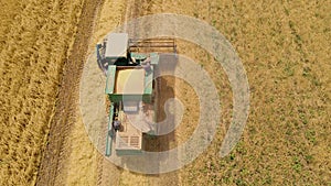 Top down view on agricultural combine harvester gathers wheat crop. Barley harvesting in large dry field