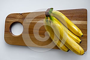 Top down view of a bunch of yellow bananas which are laying on a wooden cutting board