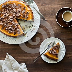 Top down view of a chocolate chunk butterscotch covered cheesecake with a slice.