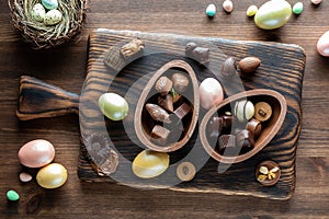 Top down view of chocolate Easter egg halves filled with gourmet chocolates surrounded by other Easter decorations.