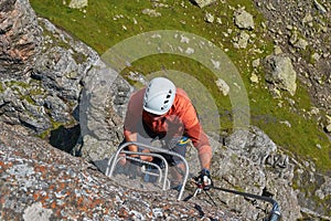 Top down view of climber on iron steps going upwards on via ferrata Delle Trincee in Dolomites, Italy, on a bright sunny day