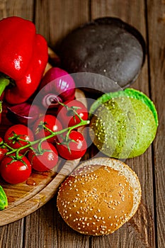 Top view closeup of three colorful hamburger buns with vegetables. Black, green, yellow buns.