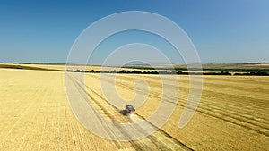 Top down view of a combine harvester working in a wheat field. The agricultural harvester machine harvests a field of