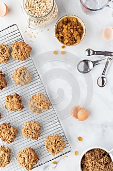 Top down view of a cooling rack filled with oatmeal raisin cookies cooling and surrounded by recipe ingredients.