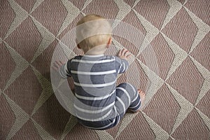 A top down view of a cute baby as they try to crawl on a carpet