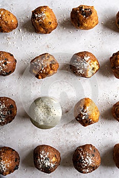 Top down view of Dutch traditional oliebollen with powdered sugar on white background, vertical