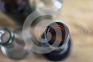 Top-Down View of Glass Bottle Rim, Bore, Orifice or Throat. Blurred Empty Glass Bottles, Wooden Background. Healthy Living and