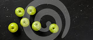 Top down view, green apples on dark marble board. Healthy food with fruit banner, space for text on right