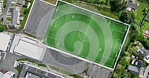 Top-down view of a green, empty football field amongst the houses 4k