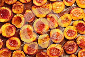 Top down view of many half sliced peaches, baked with cinnamon, butter and honey on a baking paper