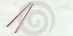 Top down view - pair of dark wood chopsticks on white board. Can be used as banner for asian / chinese food, space for text on