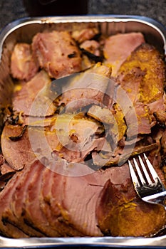 Top down view of a pan filled with slices of ham for a family gathering