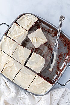 Top down view of a pan of red velvet chocolate brownies cut into squares ready for eating.