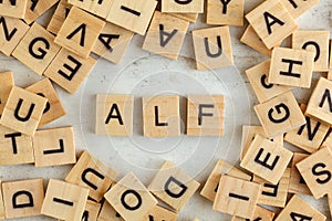 Top down view, pile of square wooden blocks with letters ALF stands for Always listen first on white board photo