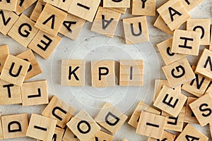 Top down view, pile of square wooden blocks with letters KPI stands for key performance indicator on white board