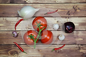 Top down view on raw uncooked isolated white and red onions, tomatoes vine and chillies. Brown natural rustic wooden background.