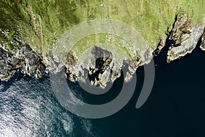 Top down view on rough coast line with green fields and cliffs by the ocean. Nobody. West of Ireland