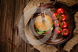 Top down view of rustic serving classic beef burger with knife on wooden table. gastro pub