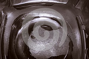 Top-down View of Square Bottom of Empty Beer Glass on Dark Table Surface. Bubbles Left from the Beer Head or Collar, Frothy Foam