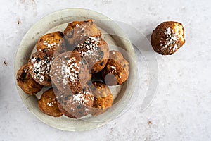 Top down view of a stack of oliebollen (Dutch dough fritters) with a glass of champagne on white background, one