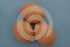 Top down view of three brown speckled chicken eggs on a blue background concept organic, free range