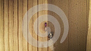 Top down view of a tractor and a combine harvester harvesting the yellow grain