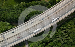 Top down view of traffic driving on the autobahn bridge between the green forest