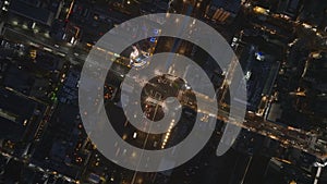 Top down view of traffic on streets in large city at night. Vehicles driving along blocks of buildings in urban borough