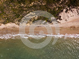 Top down view of waves breaking in the sand, flying over tropical sandy beach and waves