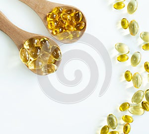 At the top of the edge there are 2 wooden spoons with capsules of omega-3 fish oil and vitamin D3 and several capsules scattered