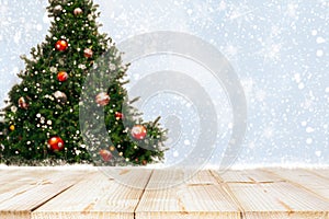 Top of empty wood table with beautiful Christmas tree and snowfall  backdrop