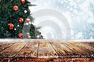 Top of empty wood table with beautiful Christmas tree and snowfall  backdrop