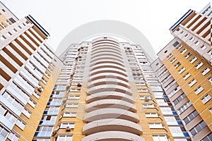 Top of facade of huge brick vivid modern gray-yellow semicircular residential building.