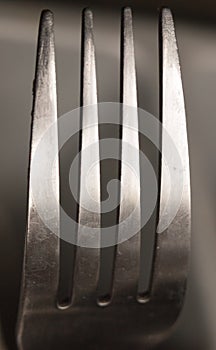 The top four prongs of a metal fork up close shining and reflect