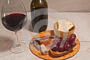 glass of red wine, bottle of wine, corkscrew, cork, rare wood bowl of red grapes