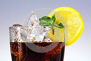 Top of a glass of cola or coke with ice cubes, lemon slice and p