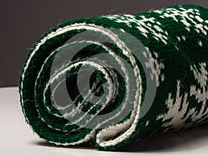 The top of the green scarf rolled into a roll on a white and gray background