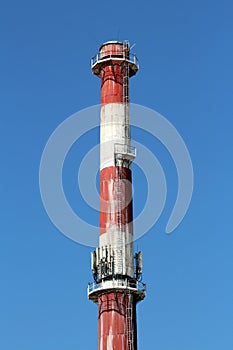 Top of high industrial red and white chimney with multiple cell phone antennas