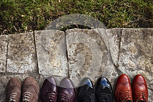 Top image of a colored a lot of pairs of a shoes, arranged down on the stone path