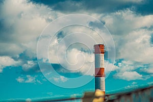 Top of industrial smoke pipe against the blue sky background. Factory chimney pipe with metal scaffolding. Smokestack