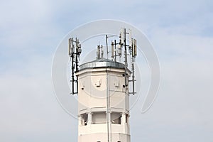 Top of large concrete industrial complex tower with multiple cell phone antennas and transmitters surrounded with security cameras