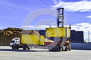 Top lift unload container from trailer at a container yard inside seaport area. Container handling, transportation, and shipping.