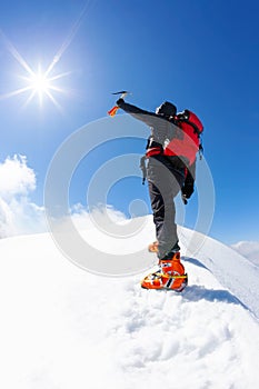 At the top: a lonely climber reaches the summit of a snowy mountain peak in winter season