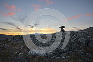 Top marked by pile of stones with vibrant yellow sunset background