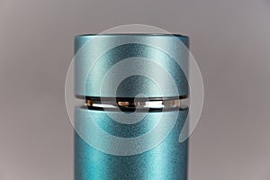 Top of modern thermos opposite gray background. Cylindrical vacuole flask in turquoise color. Container for hot and cold drinks.